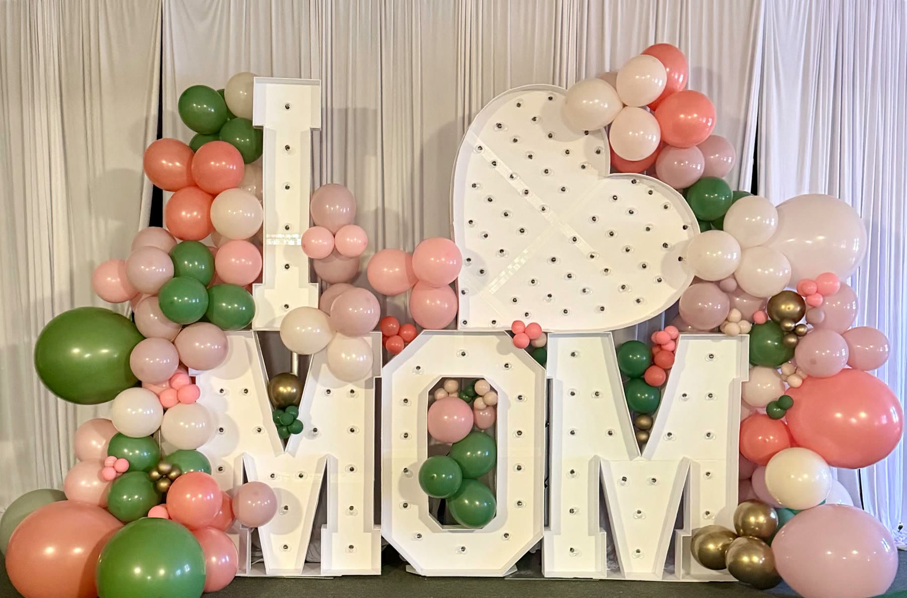Organic balloon garland in blush, sage and gold wrapped around marquee letters