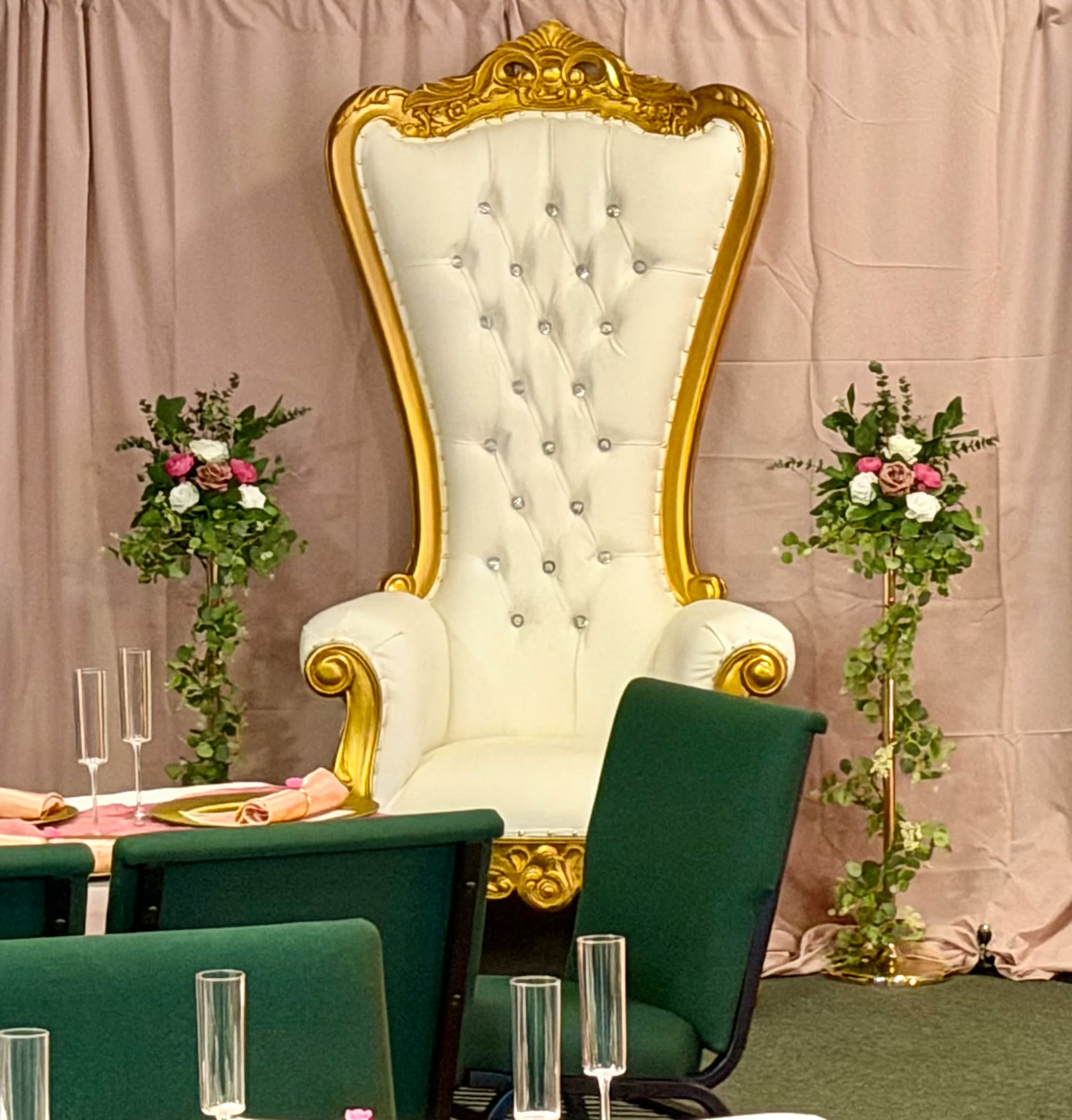 White and gold throne chair with floral stands against a blush pink backdrop
